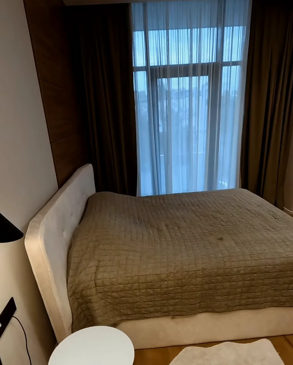 The bedroom of an apartment in Lighthouse: a double bed and a floor-to-ceiling window
