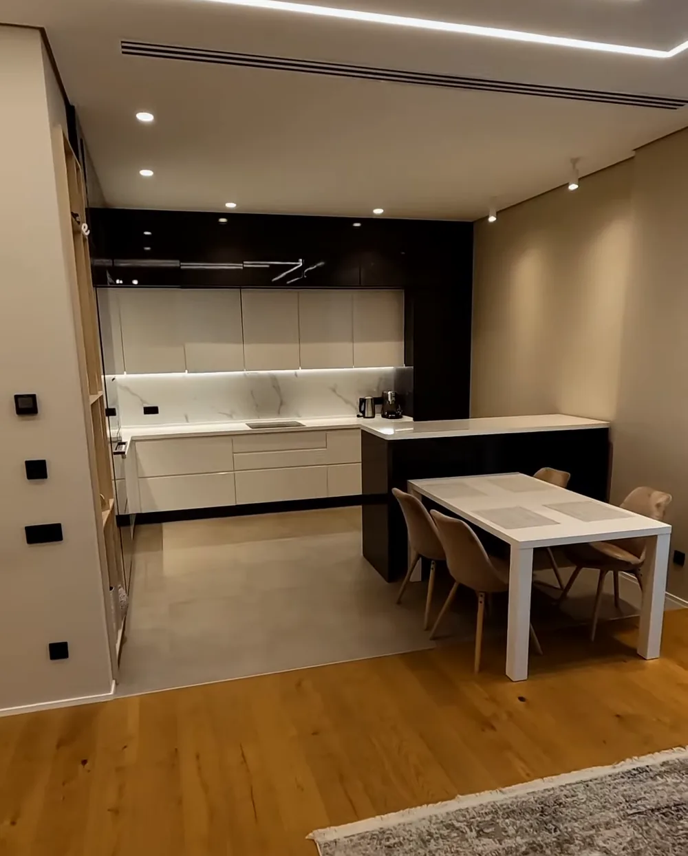 The kitchen-dining room of an apartment in Lighthouse: white cabinet fronts, an island and a table for six