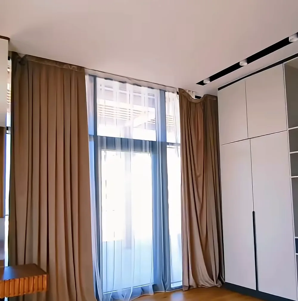 A finished apartment in Lighthouse: a floor-to-ceiling window, curtains, a wooden floor
