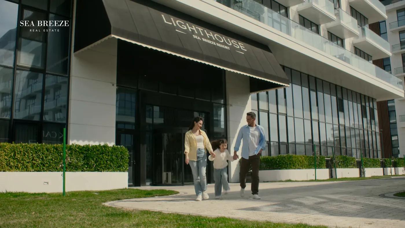 A family walks past the entrance of a Lighthouse building, with a lawn in front of it