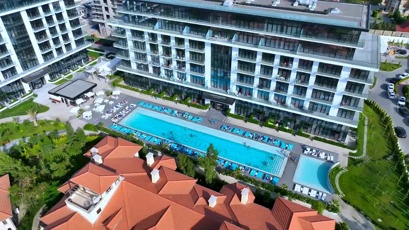 The Lighthouse courtyard from above: a long pool with sun loungers between a building and villas with red roofs