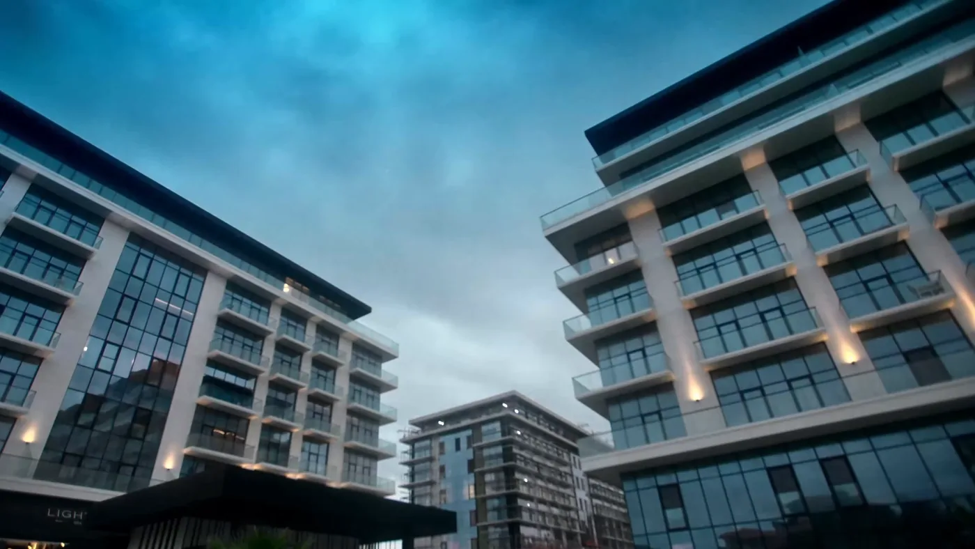 The Lighthouse buildings from below: white balcony frames and glass, evening lighting